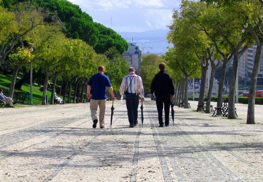 Three men walking in Parque Eduardo, Lisbon, Portugal