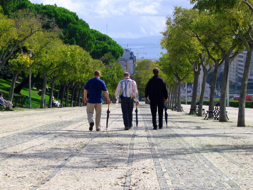 Three men walking in Parque Eduardo, Lisbon, Portugal