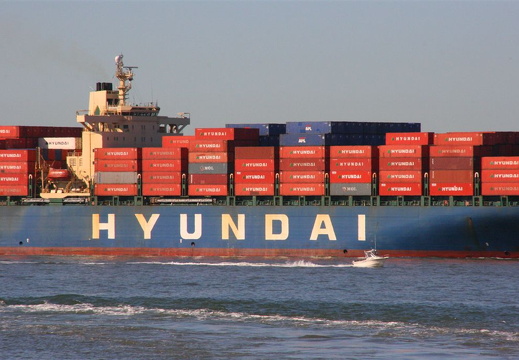 Huge cargo vessel and little flea boat