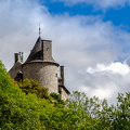 The towers of Chateau de Walzin protruding from the forest
